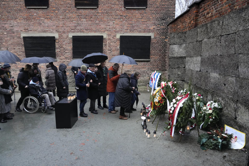 Holocaust survivors and relatives place candles next to the Death Wall in the Auschwitz Nazi death camp in Oswiecim, Poland, Saturday, Jan. 27, 2024. Survivors of Nazi death camps marked the 79th anniversary of the liberation of the Auschwitz-Birkenau camp during World War II in a modest ceremony in southern Poland.(AP Photo/Czarek Sokolowski)