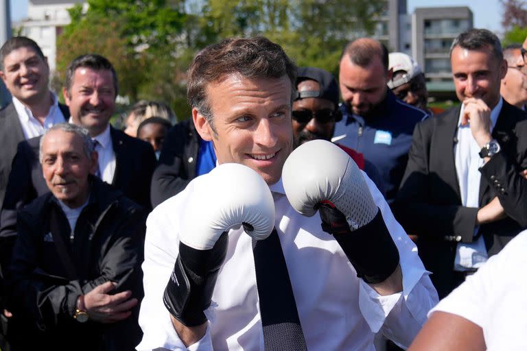 El presidente francés y candidato del partido La Republique en Marche (LREM) a la reelección, Emmanuel Macron, lleva guantes de boxeo mientras se reúne con un boxeador local en el estadio Auguste Delaune el 21 de abril de 2022 durante una visita de campaña en Saint-Denis, a las afueras de París.