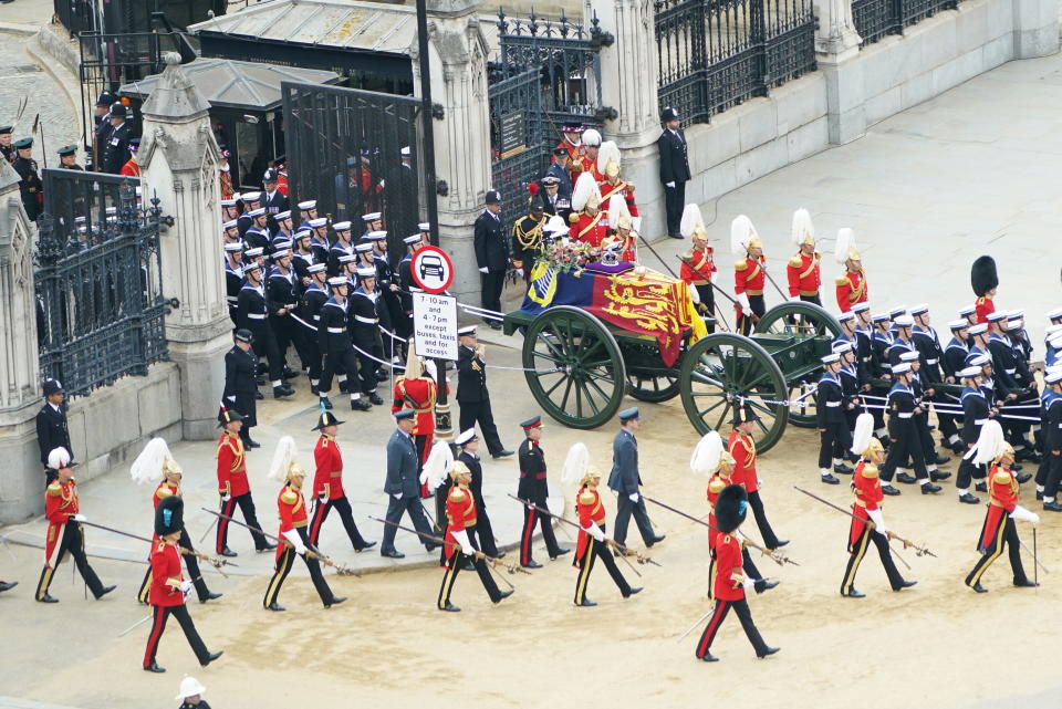 <p>The State Gun Carriage carries the Queen's coffin, draped in the Royal Standard with the Imperial State Crown and the sovereign's orb and sceptre, as it leaves Westminster Hall for Westminster Abbey.</p> 