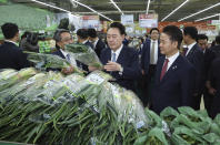 South Korean President Yoon Suk Yeol, center, checks the price of green onions at Nonghyup Hanaro Mart in Seoul, South Korea, Monday, March 18, 2024. As South Koreans prepare to vote for a new 300-member parliament next week, many are choosing their livelihoods and other domestic topics as their most important election issues. This represents a stark contrast from past elections, which were overshadowed by security and foreign policy issues like North Korean nuclear threats and the U.S. security commitment. (Yonhap via AP)