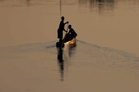 People steer a canoe on a loagoon by the bridge near the historic slave port town Ouidah