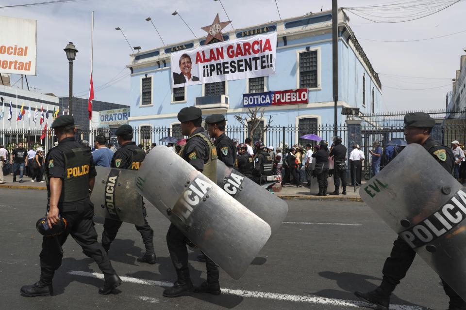Police pass the political party headquarters of Peru's late President Alan Garcia where is wake is being held in Lima, Peru, Thursday, April 18, 2019. Garcia shot himself in the head and died Wednesday as officers waited to arrest him in a massive graft probe that has put the country's most prominent politicians behind bars and provoked a reckoning over corruption. (AP Photo/Martin Mejia)