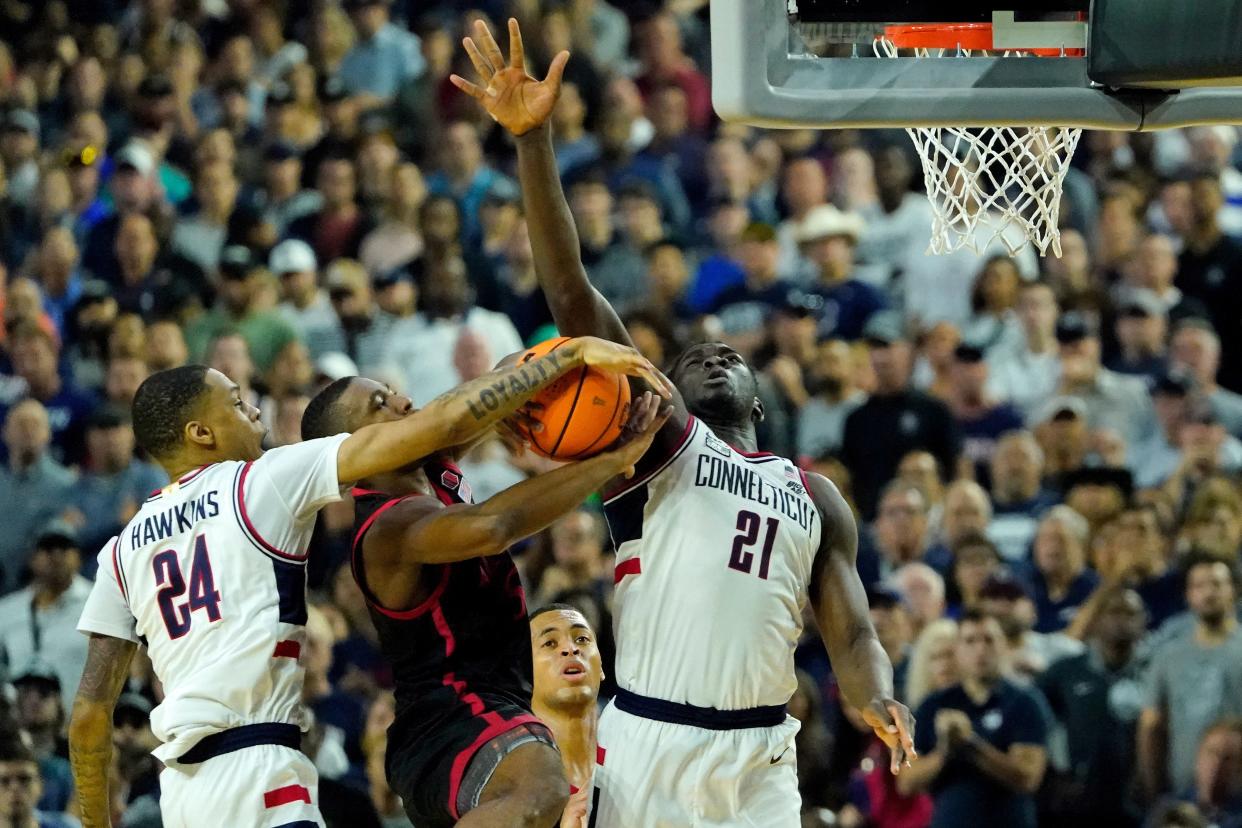 San Diego State guard Lamont Butler, the hero of the Aztecs' national semifinal win, looks for an opening against the physical defense of Connecticut guard Jordan Hawkins, left, and forward Adama Sanogo. UConn won convincingly 76-59 in Monday night's NCAA championship game.