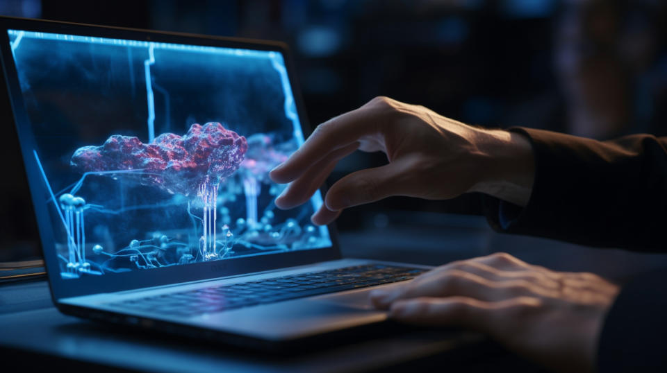 A close-up view of a scientist's hand pressing keys on a laptop as another looks closely at a 3-D model on a large monitor.