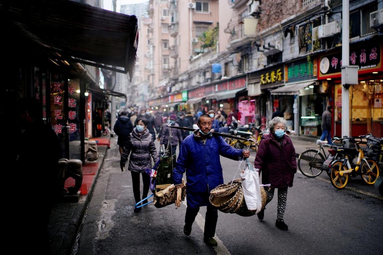 Image: People wearing protective masks walk at a street market almost a year after the start of the coronavirus disease (COVID-19) outbreak, in Wuhan, Hubei province (Aly Song / Reuters)