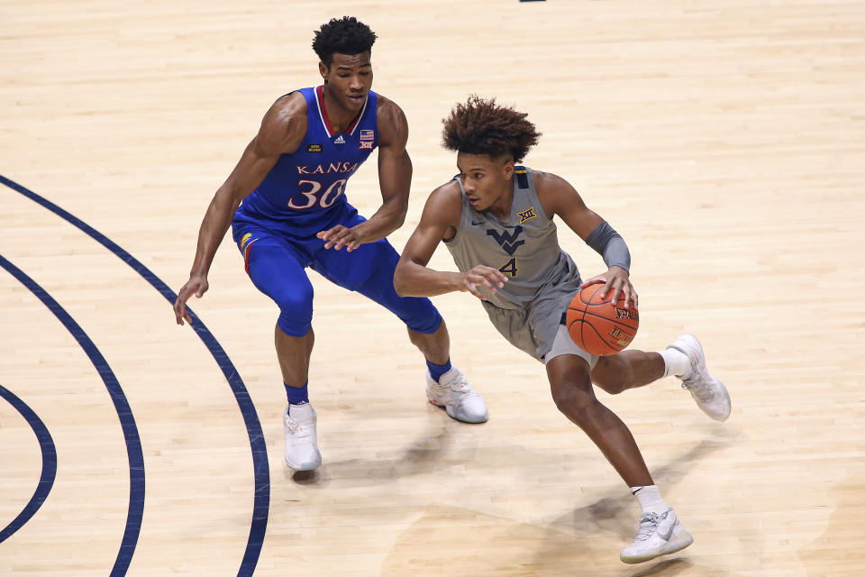 West Virginia guard Miles McBride (4) is defended by Kansas guard Ochai Agbaji (30) during the first half of an NCAA college basketball game Saturday, Feb. 6, 2021, in Morgantown, W.Va. (AP Photo/Kathleen Batten)