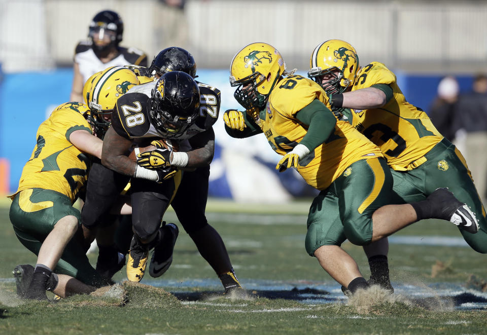 Towson running back Terrance West (28) digs up turf as North Dakota State's Colten Heagle, left, Leevon Perry (69) and Kyle Emanuel (53) combine for the stop in the second half of the FCS championship NCAA college football game, Saturday, Jan. 4, 2014, in Frisco, Texas. NDSU won 35-7. (AP Photo/Tony Gutierrez)