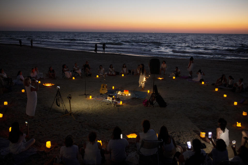 Women take part in a Tashlich ceremony, where they wrote down things they want to release before casting them into a fire, on the beach in Tel Aviv, Israel, Tuesday, Sept. 14, 2021. Tashlich, which means 'to cast away' in Hebrew, is the practice by which Jews go to a large flowing body of water and symbolically 'throw away' their sins by throwing a piece of bread, or similar food, into the water before the Jewish holiday of Yom Kippur, the holiest day in the Jewish year which starts at sundown Wednesday. (AP Photo/Maya Alleruzzo)