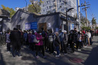 Residents wearing face masks to help curb the spread of the coronavirus line up to receive booster shots against COVID-19 at a vaccination site near a residential area in Beijing, Friday, Oct. 22, 2021. China's capital Beijing has begun offering booster shots against COVID-19, four months before the city and surrounding regions are to host the Winter Olympics. (AP Photo/Andy Wong)