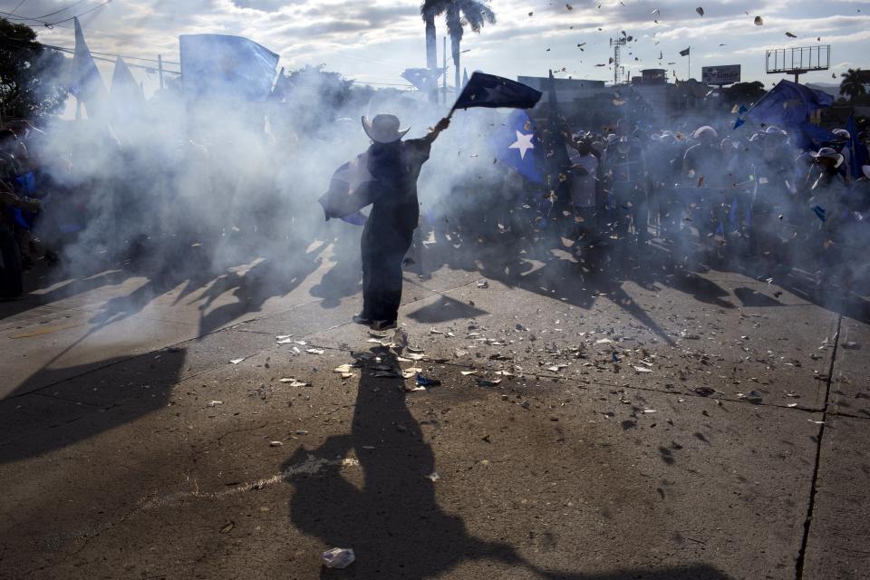 <p>A supporter of Honduran President Juan Orlando Hernandez, who is running for reelection, waves a flag amid smoke from firecrackers, during a march to show support for their candidate in Tegucigalpa, Honduras, Tuesday, Nov. 28, 2017. (Photo: Rodrigo Abd/AP) </p>