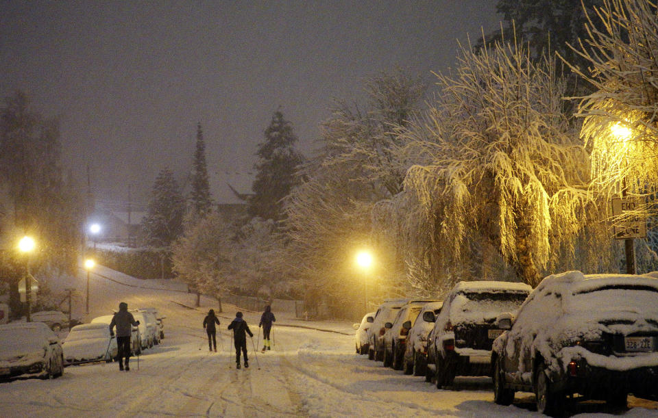 Cross country skiers travel on a street in Tacoma, Wash., the night of Friday, Feb. 8, 2019, during a storm that dropped inches of snow throughout the region and left trees and cars coated in snow and ice. (AP Photo/Ted S. Warren)