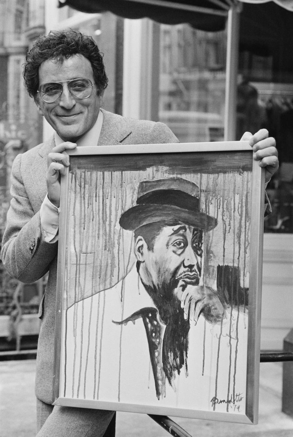 Holding one of his paintings, which he created under the name Anthony Benedetto, in 1977 (Getty)