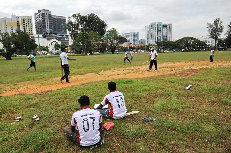 South Asian workers play a cricket game on the field next to Little India district in Singapore on December 15, 2013