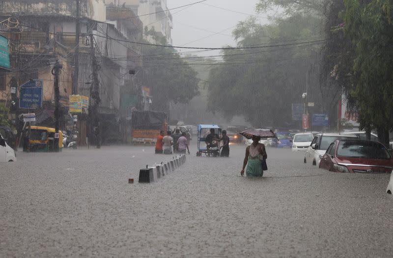 People wade through a flooded street after heavy rains in New Delhi