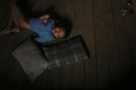 Tin Aung Zin, a nine-year-old Rohingya boy in a coma which his mother says was caused by shock during the communal violence in their former neighbourhood Nahzi village in Sittwe, lies on the floor inside their new home at a village near the Thet Kae Pyin camp for internally displaced people in Sittwe, Rakhine state, April 23, 2014. REUTERS/Minzayar