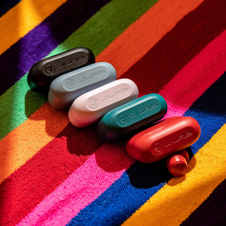 Four JLab earbud cases on a multicolored striped background