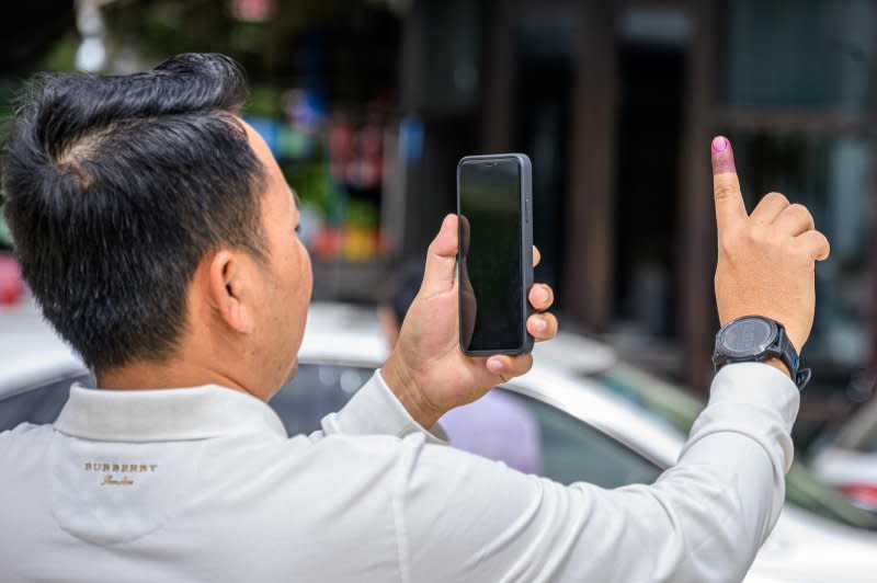 A voter takes a photo of his finger, dyed purple after voting. Photo by Thomas Maresca/UPI