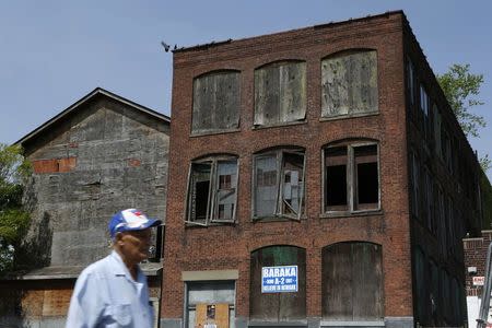 A man walks past an abandoned house with a poster of Newark's mayoral candidate Ras Baraka during mayoral elections in Newark, New Jersey, in this May 13, 2014 file photo. REUTERS/Eduardo Munoz/Files