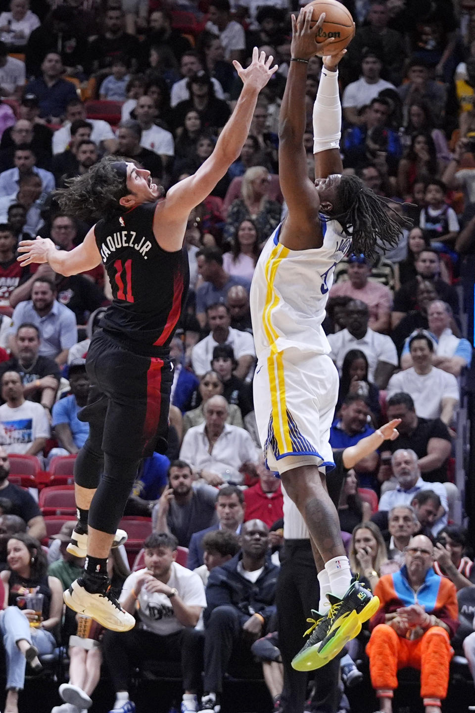 Golden State Warriors forward Kevon Looney, right, leaps up for a pass as Miami Heat guard Jaime Jaquez Jr. (11) attempts the steal during the first half of an NBA basketball game, Tuesday, March 26, 2024, in Miami. (AP Photo/Wilfredo Lee)