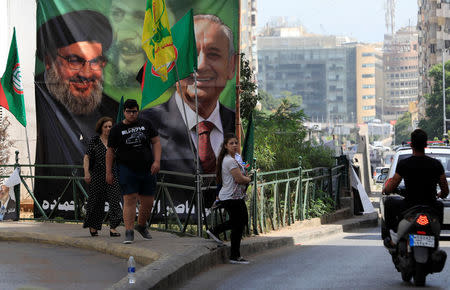 People walk past a campaign banner showing Lebanese Parliament Speaker and candidate for parliamentary election Nabih Berri and Hezbollah leader Sayyed Hassan Nasrallah in Beirut, Lebanon May 4, 2018. REUTERS/Jamal Saidi