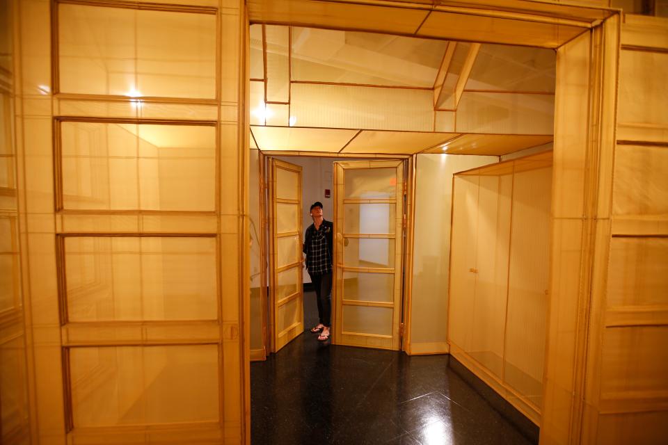 Lindsay Mis, director of DATMA, puts the finishing touches on the fragile doors of the 'fabric architecture' piece by Do Ho Suh.  This piece and many others are on display now at the UMass Dartmouth CVPA gallery in downtown New Bedford.