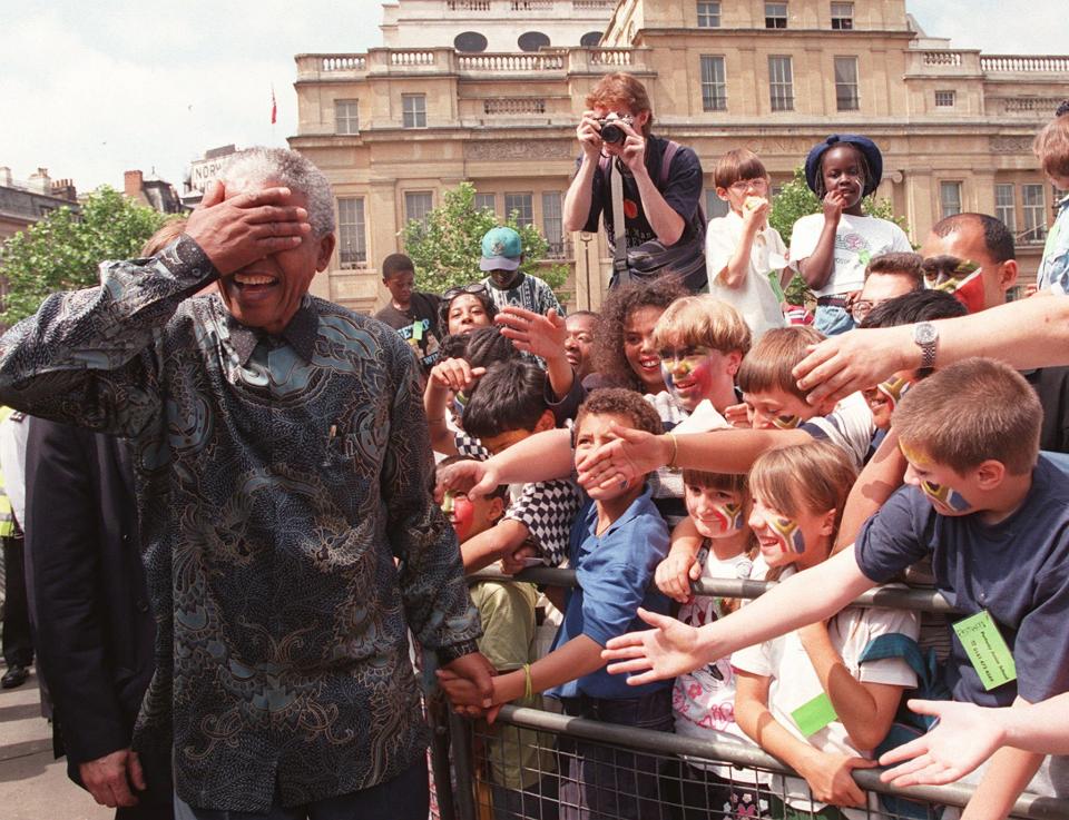 FILE - South Africa's President Nelson Mandela reacts as he walks amongst the vast Trafalgar Square crowd in London Friday July 12 1996. Caulkin, a retired Associated Press photographer who captured the iconic moment when ice dancers Jayne Torvill and Christopher Dean won the 1984 Olympic gold medal, has died. He was 77 and suffered from cancer. (AP Photo/Dave Caulkin, File)