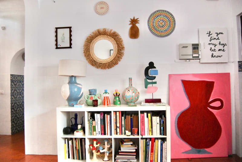 Colorful amp and decor on top of cube bookcase in white living room.