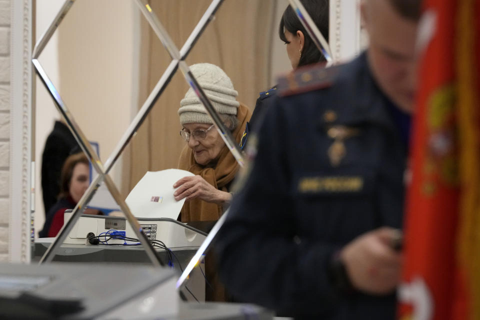 An elderly woman is reflected in a mirror as she casts a ballot at a polling station during the presidential elections in St. Petersburg, Russia, Saturday, March 16, 2024. Voters in Russia are heading to the polls for a presidential election that is all but certain to extend President Vladimir Putin's rule after he clamped down on dissent. (AP Photo/Dmitri Lovetsky)