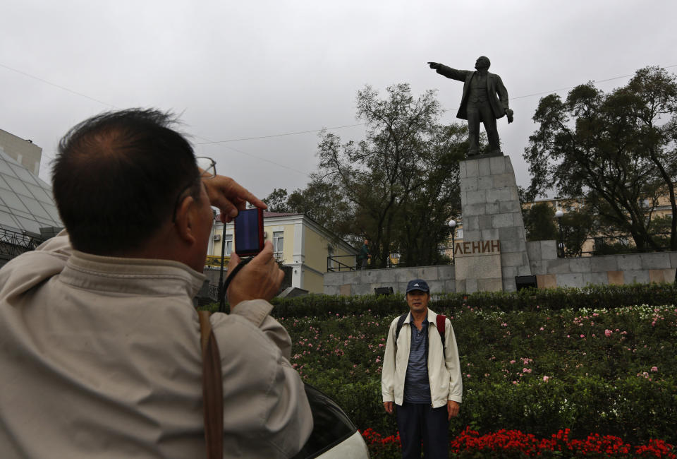 A Chinese tourist poses for a photo in front of a statue of Lenin in the eastern Russian city of Vladivostok Wednesday, Sept. 5, 2012. Once a mysterious closed city during Soviet times, Vladivostok is ready to strut in the world spotlight as host of the Asia-Pacific Economic Cooperation summit. Russia has splashed $20 billion preparing for the summit in Vladivostok, its largest but long-neglected Pacific port, as part of a grand plan to become a bigger player on Asian markets. (AP Photo/Vincent Yu)