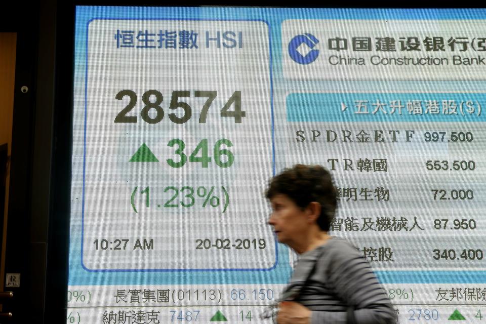 A woman walks past an electronic board showing Hong Kong share index outside a bank in Hong Kong, Wednesday, Feb. 20, 2019. Shares were mostly higher in Asia on Wednesday after a modestly high finish on Wall Street that extended the market’s gains into a fourth week.(AP Photo/Kin Cheung)