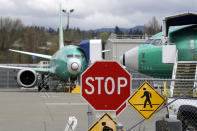 FILE - In this April 8, 2019, file photo Boeing 737 Max 8 jets are parked behind a stop sign indicating a traffic crossing at a Boeing Co. production facility in Renton, Wash. On Monday, Dec. 16, shares of Boeing are falling before the opening bell on a report that the company may cut production of its troubled 737 Max or even end production all together. (AP Photo/Elaine Thompson, File)