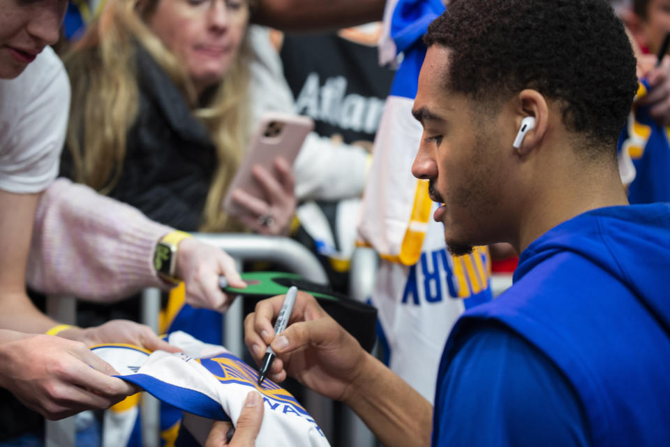 Golden State Warriors guard Jordan Poole, right, gives autographs before an NBA basketball game against the Atlanta Hawks, Friday, March 17, 2023, in Atlanta. (AP Photo/Hakim Wright Sr.)