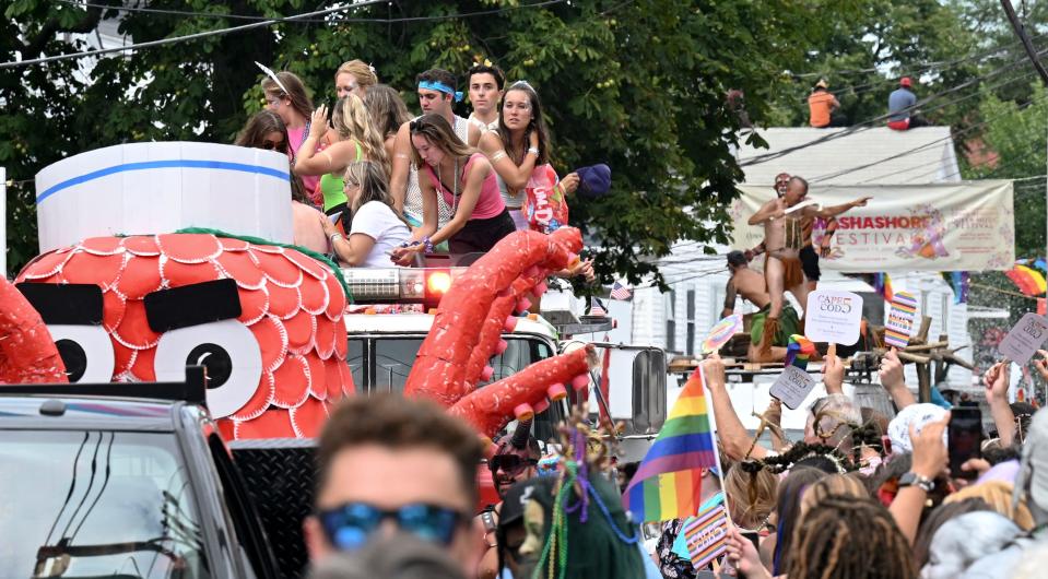 People adorn the "Monsters, Myths & Legends" floats crawling down Commercial Street.