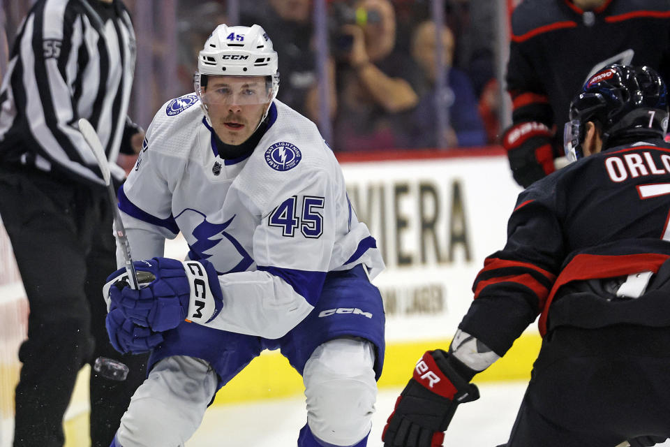 Tampa Bay Lightning's Cole Koepke (45) chips the puck past Carolina Hurricanes' Dmitry Orlov (7) during the first period of an NHL hockey game in Raleigh, N.C., Friday, Nov. 24, 2023. (AP Photo/Karl B DeBlaker)