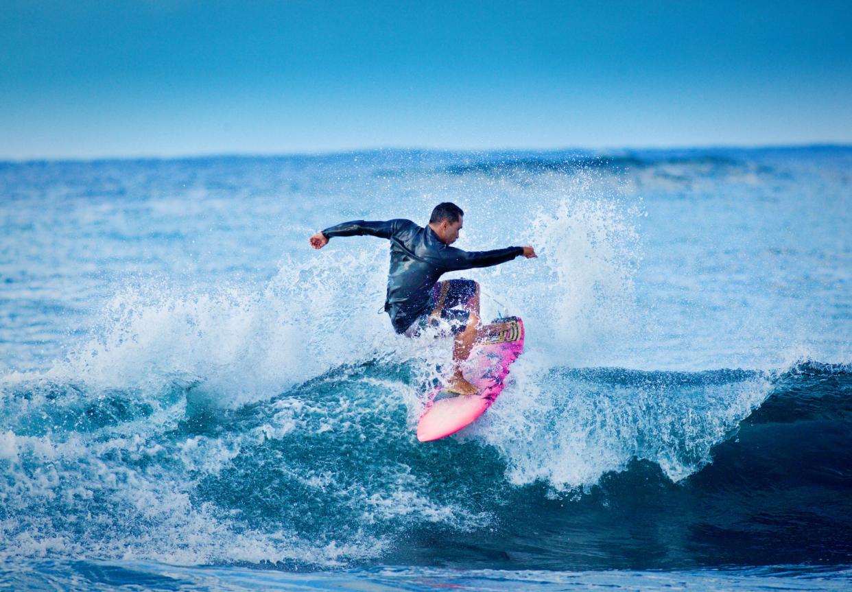 A local Hawaiian surfer surfing at Poipu Beach, Kauai, Hawaii.