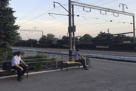 Men look at tanks on cars shortly after the arrival of the freight train at a railway station in the Russian southern town of Matveev Kurgan, near the Russian-Ukrainian border in Rostov region, Russia, May 26, 2015. REUTERS/Maria Tsvetkova