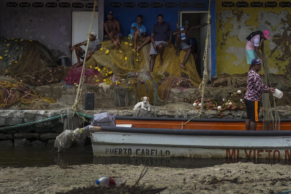 Varios pescadores, sentados sobre sus redes en Choroni, en el estado venezolano de Aragua, el 6 de junio de 2023. (AP Foto/Matías Delacroix)