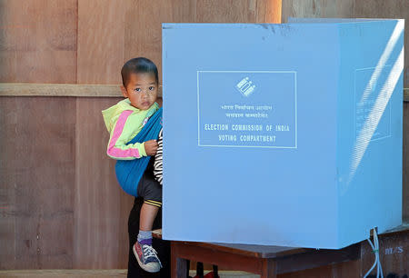 A woman holds her child as she casts her vote a polling station during state assembly elections at Kanhmun village, in the northeastern state of Mizoram, India, November 28, 2018. REUTERS/Jayanta Dey