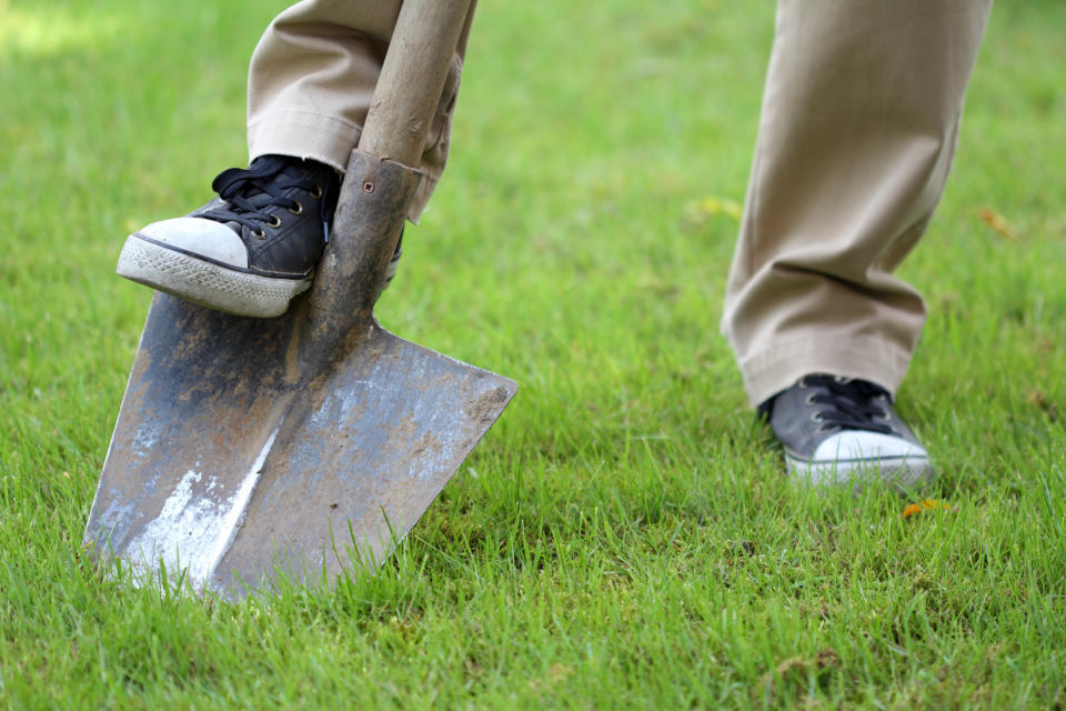 A person's foot rests on a shovel