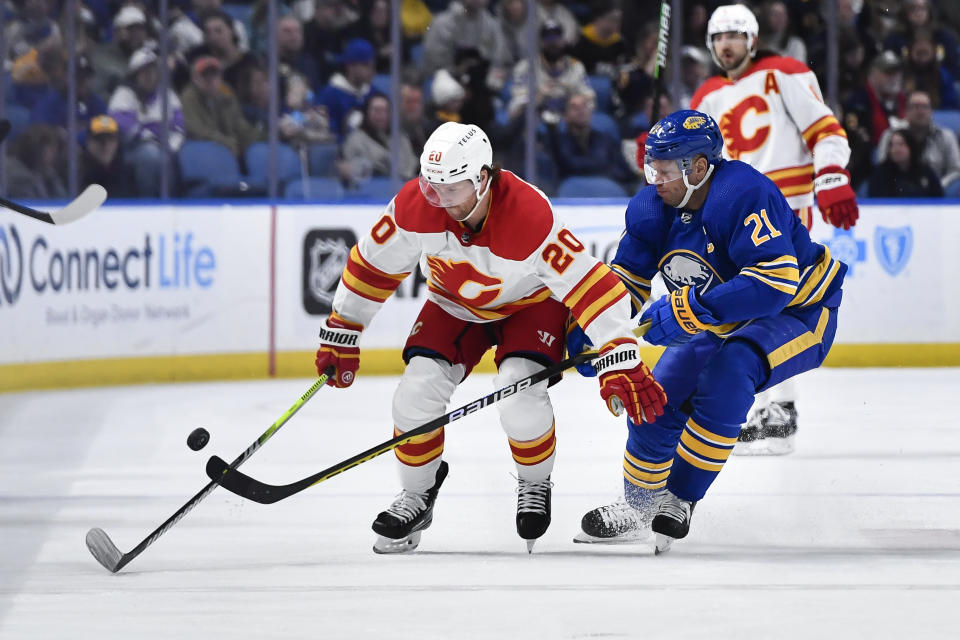 Buffalo Sabres right wing Kyle Okposo, right, tips the puck away from Calgary Flames center Blake Coleman during the first period of an NHL hockey game in Buffalo, N.Y., Saturday, Feb. 11, 2023. (AP Photo/Adrian Kraus)