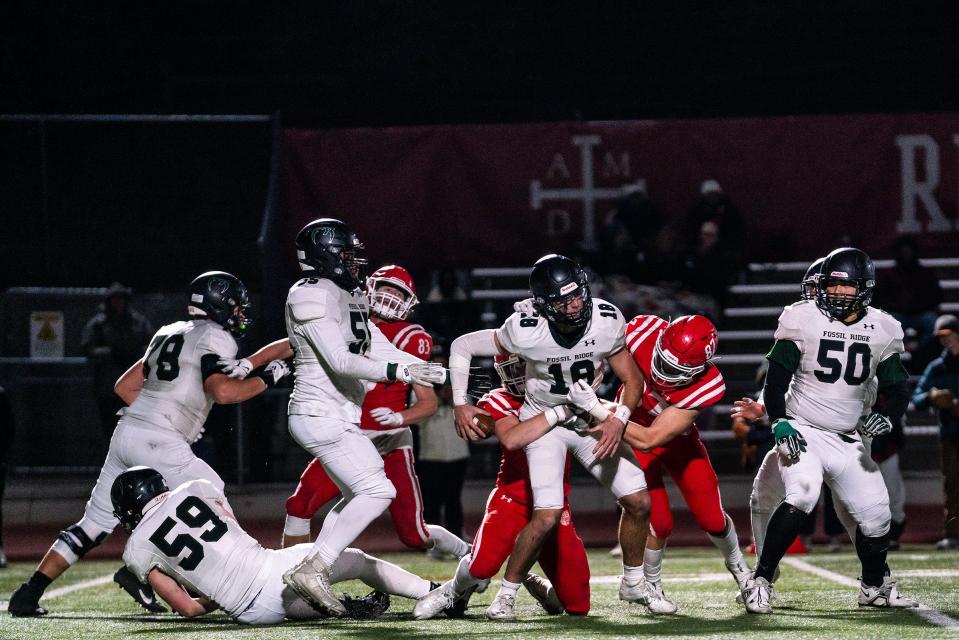 Fossil Ridge's Tyler Kubat (18) tries to avoid a tackle during a Class 5A football playoff game vs. Regis Jesuit in Aurora, Colo. on Friday, Nov. 11, 2022.