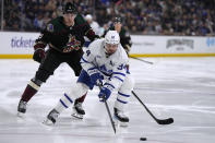 Toronto Maple Leafs center Auston Matthews (34) carries the puck in front of Arizona Coyotes defenseman Michael Kesselring during the second period of an NHL hockey game Wednesday, Feb. 21, 2024, in Tempe, Ariz. (AP Photo/Rick Scuteri)
