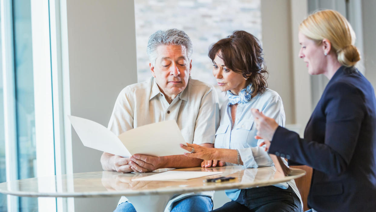A senior couple sitting down with a personal consultant, perhaps a financial advisor to discuss their retirement plans, or maybe a realtor or insurance agent.