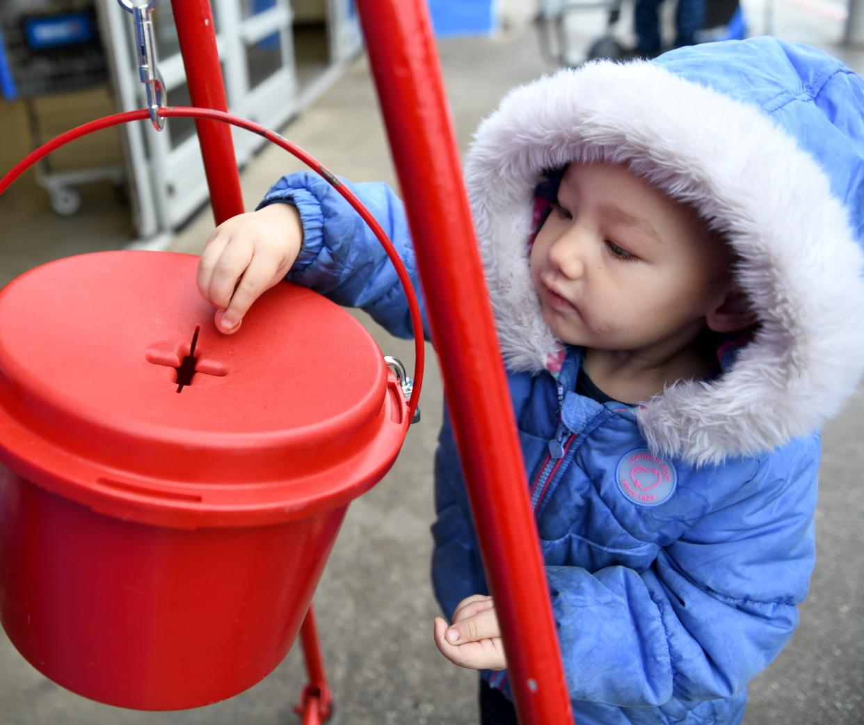 Ka'Myah Todd drops change into a Salvation Army kettle on Wednesday, Dec. 7, 2022, at Walmart.