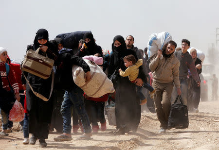 People walk with their belongings as they flee the rebel-held town of Hammouriyeh, in the village of Beit Sawa, eastern Ghouta, Syria March 15, 2018. REUTERS/Omar Sanadiki