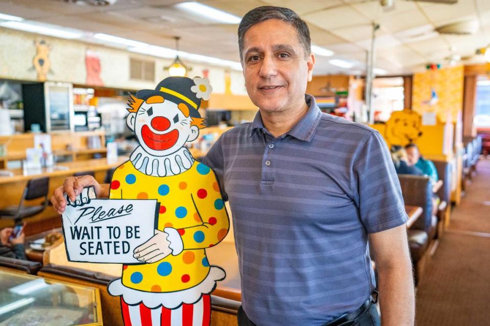 Adnan Anwar, owner of Pancake Circus, stands next to the restaurant’s iconic wooden cut-out clown earlier this month.
