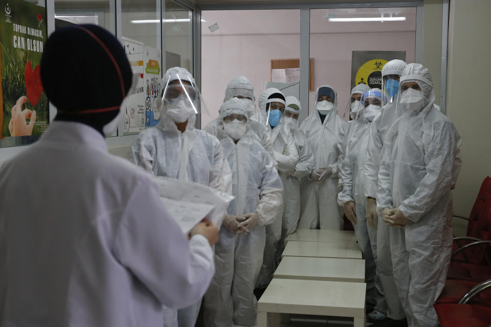 In this Friday, May 15, 2020 photo, Dr. Melek Nur Aslan, left, the local health director for Fatih, a large district in the historic peninsula of Istanbul briefs a team of contact tracers with Turkey's Health Ministry's coronavirus contact tracing team, clad in white protective gear, masks and face shields. Teams of contact tracers in Istanbul, the epicenter of the pandemic in Turkey and its most populous city, and also nationwide, are going house to house to test people experiencing COVID-19 symptoms and inform patients on isolation. (AP Photo/Emrah Gurel)