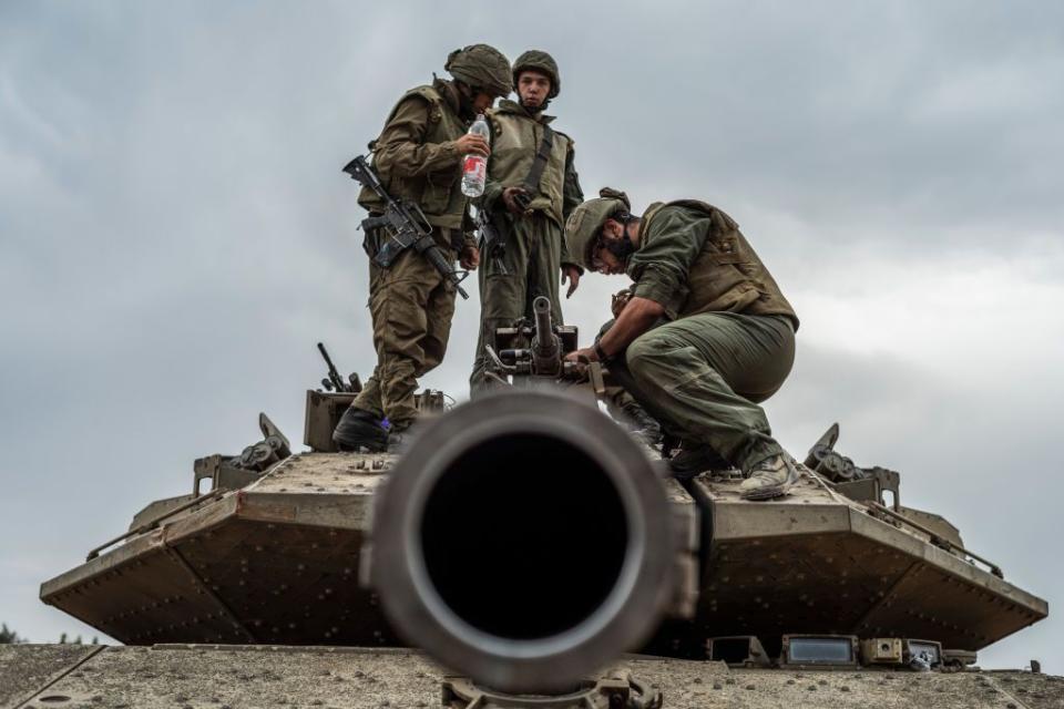 An Israeli soldier works on a tank at the Israel-Gaza border.