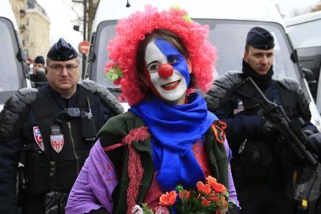 An environmentalist wears a red nose as she demonstrates near French riot police in Paris, France, as the World Climate Change Conference 2015 (COP21) continues at Le Bourget, December 12, 2015. REUTERS/Pascal Rossignol