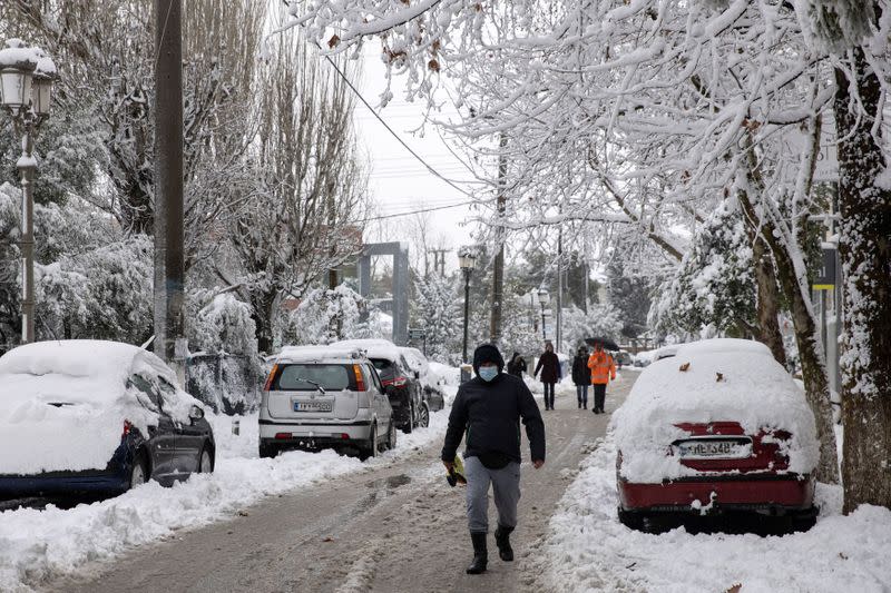 Un hombre con una máscara protectora se aleja después de las fuertes nevadas, en la aldea de Krioneri, Grecia, el 15 de febrero de 2021.